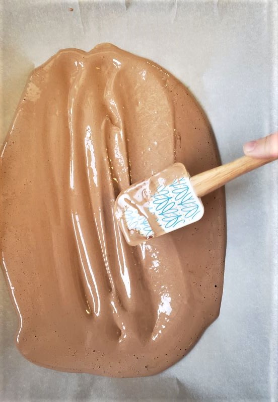 Pouring chocolate batter into pan. Spreading chocolate cake batter with a spatula.