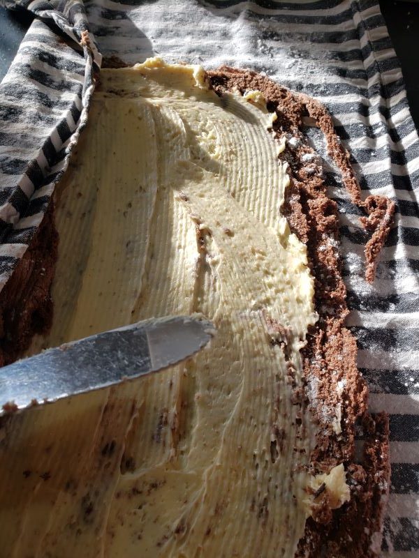 Spreading frosting on a chocolate unelmatorttu. Spreading frosting on a chocolate roll cake.