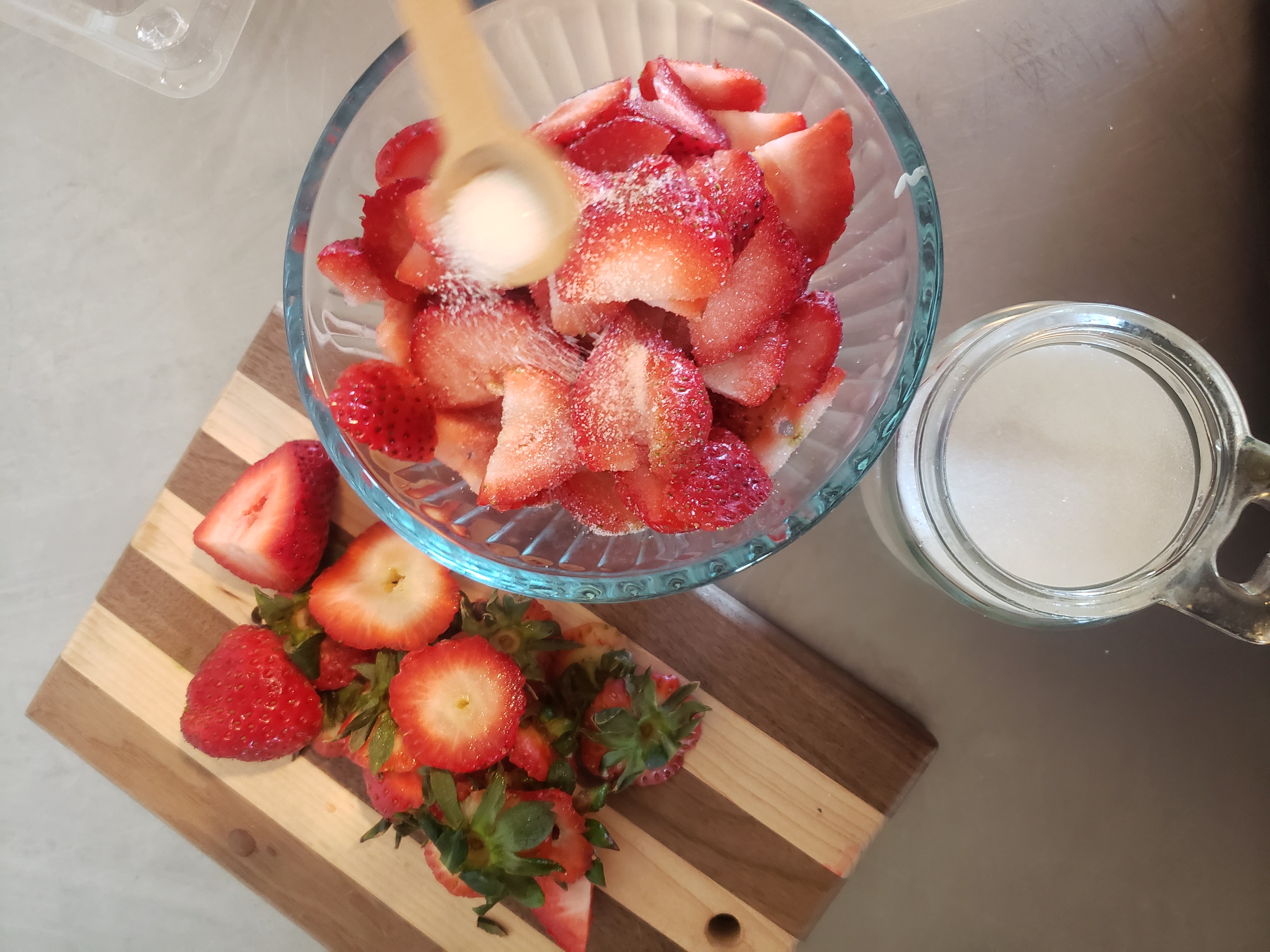 Sugar being added to sliced strawberries